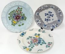 Three tin-glazed earthenware plates, decorated with polychrome floral motifs. (3)