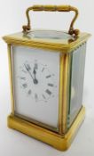 A brass-cased carriage clock, the dial with roman numerals and outer track arabic numerals, striking