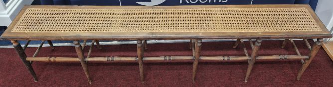 A 19th century long caned seat bench, on turned legs, length 183cm, height 43cm.