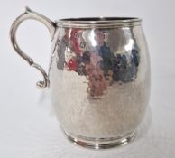 A large silver mug or tankard with hammered design and scroll handle, hallmarked London 1945