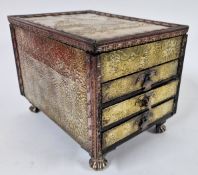 A brass and copper elaborately embossed jewellery box, with three drawers, and lift up lid, on