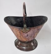 A copper coal scuttle with handle.