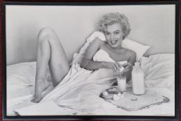 A large scale print of a photograph of Marilyn Monroe in bed, framed and glazed, subject 57cm x 87.