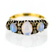 An 18ct three stone opal and diamond ring, set with eight diamonds, circa 1900, size Q/R.