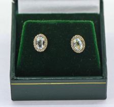 A pair of 9ct yellow gold oval aquamarine and round brilliant cut diamond cluster studs, aquamarines