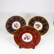 Caverswall China cabinet plates decorated with flowers, two blue and one red. D.27.5cm (3)