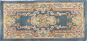 Wool rug with lined back in floral design of turquoise, pinks, cream. measures 118cm long x 60cm