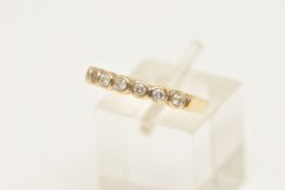 A MODERN DIAMOND BAND RING, seven round brilliant cut diamonds bezel set in yellow gold, approximate