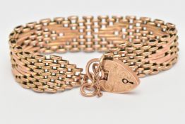 A YELLOW METAL BRACELET, a textured brick link style bracelet, fitted with a heart padlock clasp and