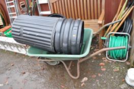 A PLASTIC BUILDERS WHEELBARROW , four plastic dustbins with lids and a selection of garden tools