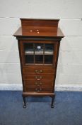 AN EDWARDIAN MAHOGANY MUSIC CABINET, with a raised back, the single door with six glass panes, above