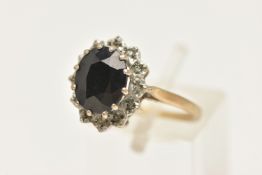 A 9CT GOLD SAPPHIRE CLUSTER RING, of an oval form, set with a central oval cut deep blue sapphire,
