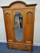 A 20TH CENTURY OAK WARDROBE, with an arched cornice, an oval mirrored door, above a single drawer,