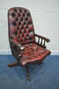 AN OXBLOOD BUTTONED SWIVEL OFFICE CHAIR, with spindled armrests, on brass castors, width 60cm x