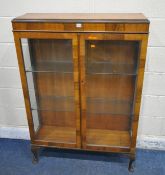 A 20TH CENTURY DISPLAY CABINET, the double glazed doors enclosing glass shelves, raised on