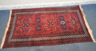 A RED GROUND RECTANGULAR RUG, with repeating geometric patterns, surrounded by a multi-strap border,
