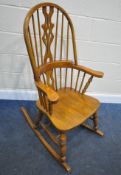 A 20TH CENTURY OAK ROCKING CHAIR, with a central splat, swept armrests, raised on turned supports,