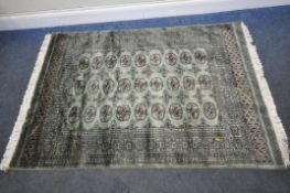 A GREEN GROUND WOOLEN HAND KNOTTED PAKISTANI RUG, with twenty-seven central medallions, surrounded