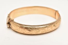 A 9CT GOLD HINGED BANGLE, foliate pattern with rope twist rim, fitted with a push button clasp and