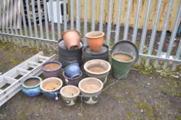 A COLLECTION OF GLAZED PLANT POTS AND PLASTIC POT PLATES including a graduated green set of three (