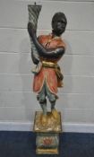A REPRODUCTION PAINTED BLACKAMOOR FIGURE, holding a spiral item, standing on a rock, atop a fixed