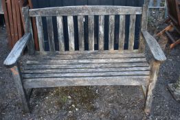 A WEATHERED SLATTED TEAK GARDEN BENCH, length 130cm, condition report: rickety and not