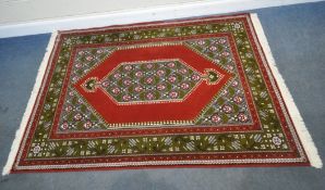 A RED AND GREEN GROUND RECTANGULAR RUG, with repeating geometric patterns, 216cm x 151cm,