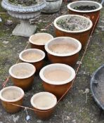 NINE BROWN GLAZED PLANTS POTS, all similar in styles and graduated in size, largest diameter 38cm