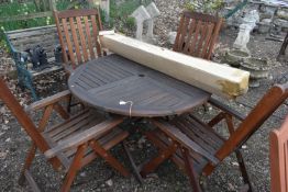 A TEAK CIRCULAR FOLDING GARDEN TABLE, diameter 110cm x height 74cm, four folding chairs and a 2.7m