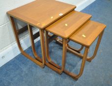 PARKER KNOLL, A MID-CENTURY TEAK NEST OF THREE TABLES, raised on shaped legs, largest table width