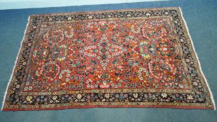 A RED GROUND RECTANGULAR WOOLEN RUG, with repeating foliate patterns, surrounded by a multi-strap