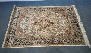 AN INDIAN KESHAN SYNTHETIC SILK RECTANGULAR RUG, with repeating foliate patterns, surrounded by a