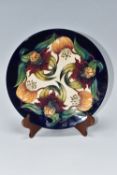 A MOORCROFT POTTERY 'ANNA LILY' SHALLOW DISH on a cobalt ground, with tube lined pattern designed by