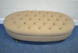 WESLEY BARRELL, A BEIGE BUTTONED UPHOLSTERED OVAL STOOL, raised on turned legs, with brass caps