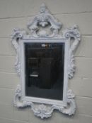 A MODERN WHITE PAINTED RESIN WALL MIRROR, with scrolled and foliate designs, width 82cm x height