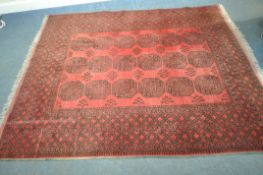 A RED GROUND AFGHAN RUG, with eighteen elephant foot medallions, surrounded by a multi-strap border,