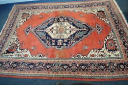 A LARGE RECTANGULAR RED GROUND WOOLLEN RUG, with a central medallion, repeating geometric