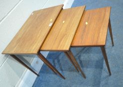 A MID-CENTURY TEAK NEST OF THREE TABLES, raised on cylindrical tapered legs, width 56cm x depth 38cm