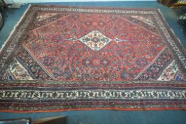 A LARGE RED GROUND WOOLLEN RUG, with repeating foliate and geometric patterns, 368cm x 260cm,