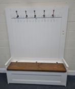 A PARTIALLY WHITE PAINTED SETTLE, with five coat hooks, a shelf, and a hinged seat, width 151cm x