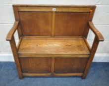 A 20TH CENTURY OAK SETTLE, with a hinged seat, and open armrests, width 83cm x depth 40cm x height