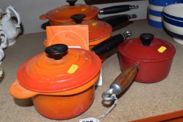 FOUR GRADUATED LE CREUSET SAUCEPANS, comprising three flame orange covered saucepans, sizes 20,