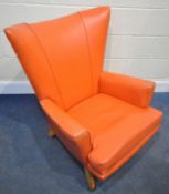 POSSIBLY G PLAN, A MID-CENTURY CORAL ORANGE LEATHERETTE WING BACK ARMCHAIR, raised on square tapered
