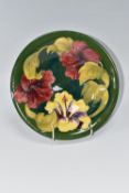 A MOORCROFT POTTERY 'HIBISCUS' BOWL on a green ground with a tube line pattern of three flowers in