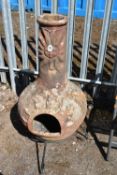 A WEATHERED TERRACOTTA CHIMINEA, with sunburst decoration, on a metal stand, height 110cm x diameter
