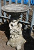 A WEATHERED COMPOSITE BIRD BATH, raised on cherub and dog support, diameter 42cm x height 77cm,