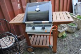 A 'BEEFMASTER' GAS BARBECUE ON TEAK STAND, with a domed lid concealing a griddle and a plate on