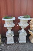 A PAIR OF CONCRETE GARDEN URNS ON STANDS, with balustered bowl featuring dual mask handles and
