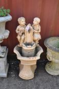 A MODERN CONCRETE GARDEN WATER FEATURE, in the form of two small children sat by a drinking