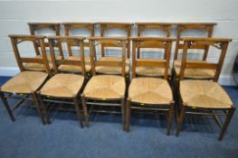 A SET OF TEN 20TH CENTURY OAK RUSH SEATED CHAIRS, with trefoil designs to the top rail, raised on